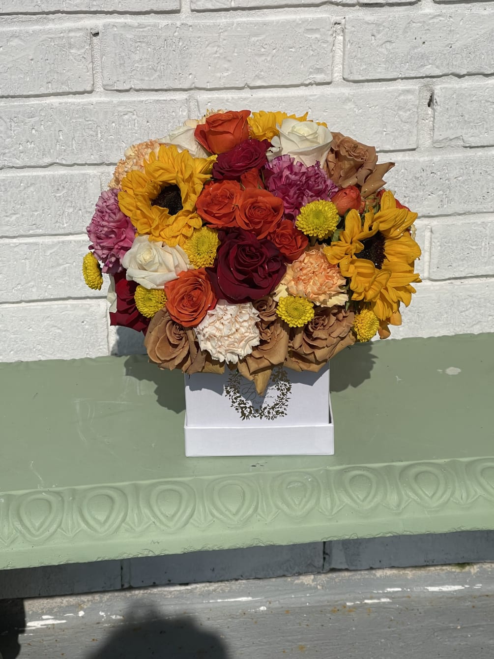 a beautiful box filled with roses, sunflowers, carnations and a variety of