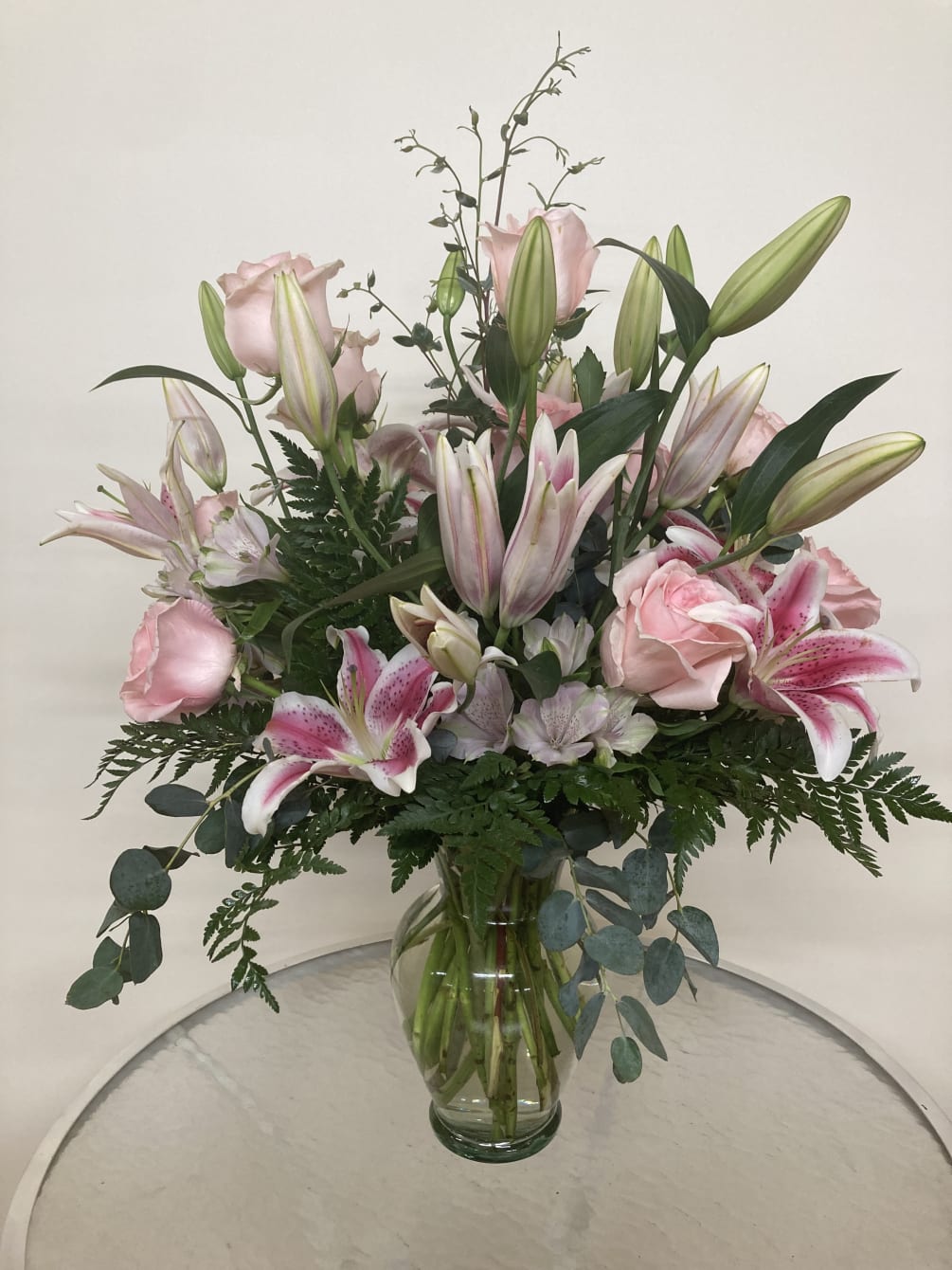 Stargazers and pink roses share space among the eucalyptus and leatherleaf.