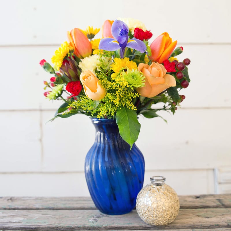 Blue vase with a Colorful mix of Roses, Iris, Mini Carnations and