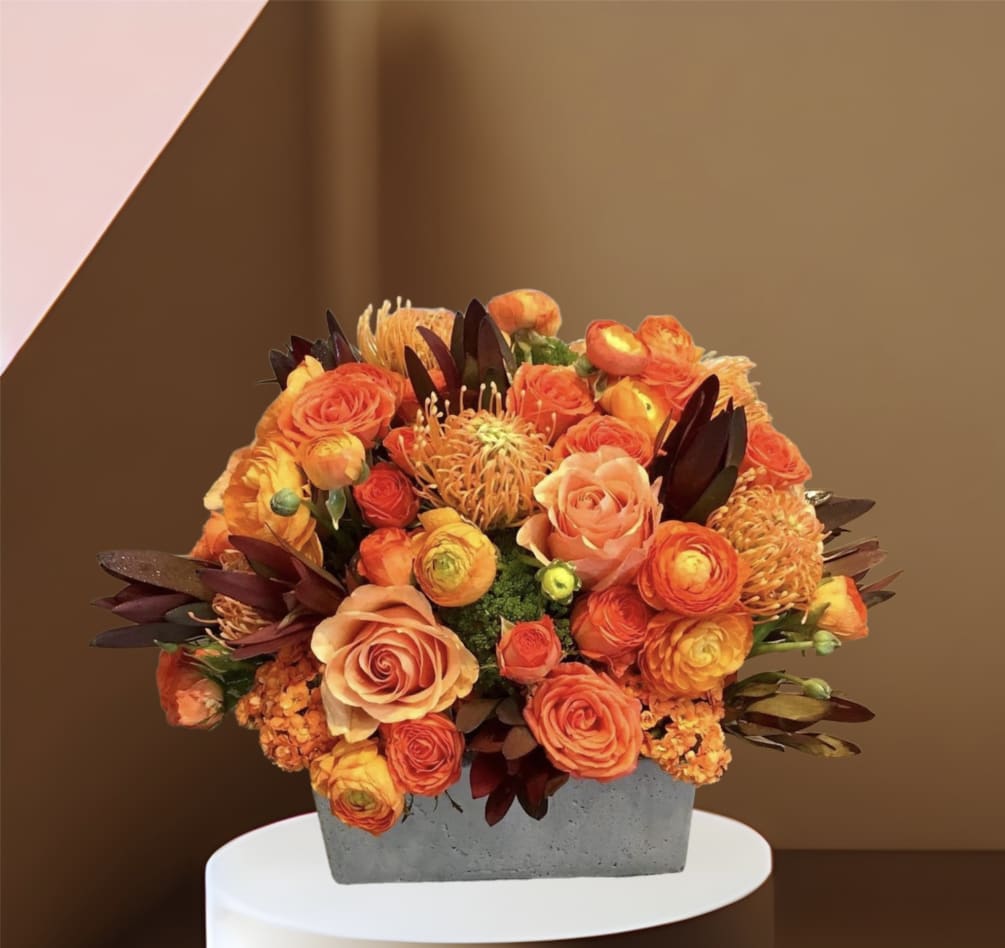 A large arrangement of fall colored roses, ranunculus, protea and other seasonal
