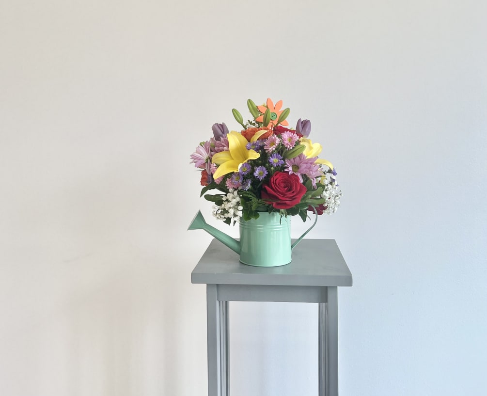 This unique summer bouquet comes in assorted color watering cans with fresh