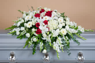 A funeral casket spray consisting of snapdragons, gladiolas, roses, buttons, carnations, hydrangeas