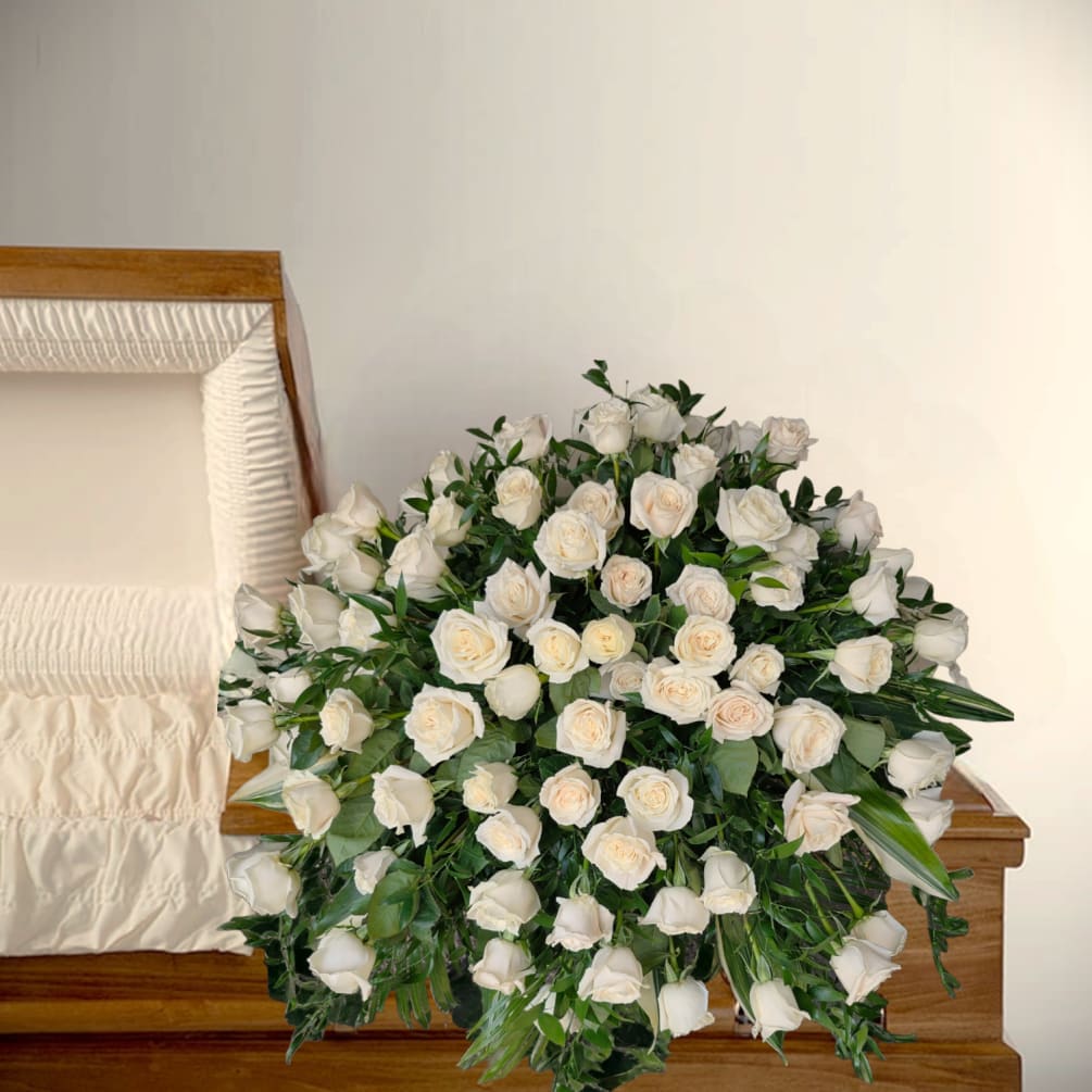 Roses and lush greens blanket the casket in a display that is