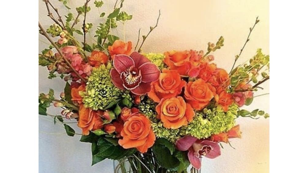 Send a refreshing splash of orange roses with orchids.