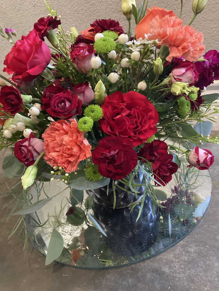 Red and red-tinged roses with red and salmon-colored carnations among white Lisianthus