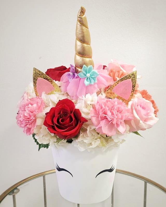 Pastel colored mixed florals with unicorn accessories in a ceramic vase.

 
The