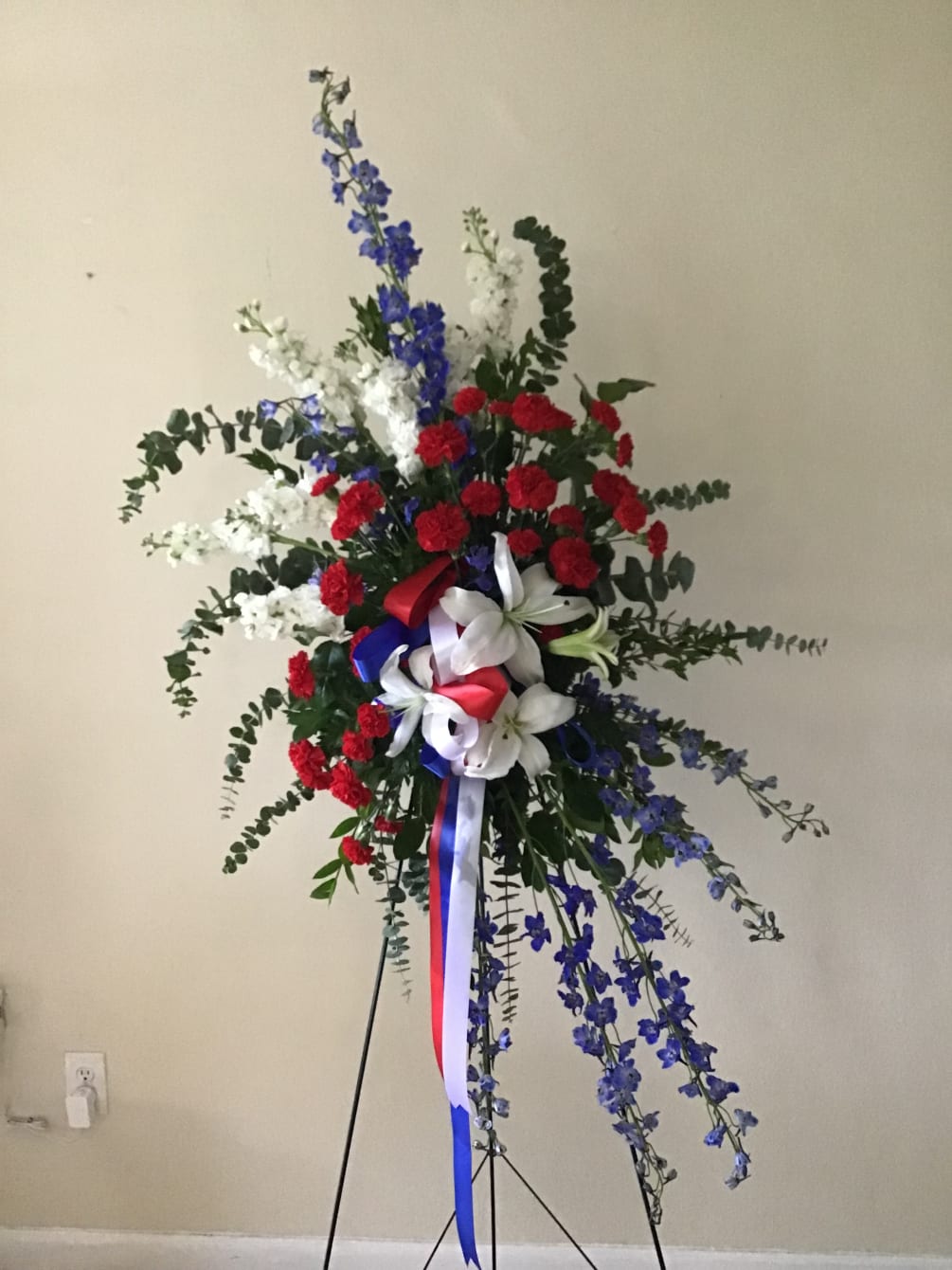 Beautiful blue delphinium, red carnations, white stocks, white lilies and greenery with