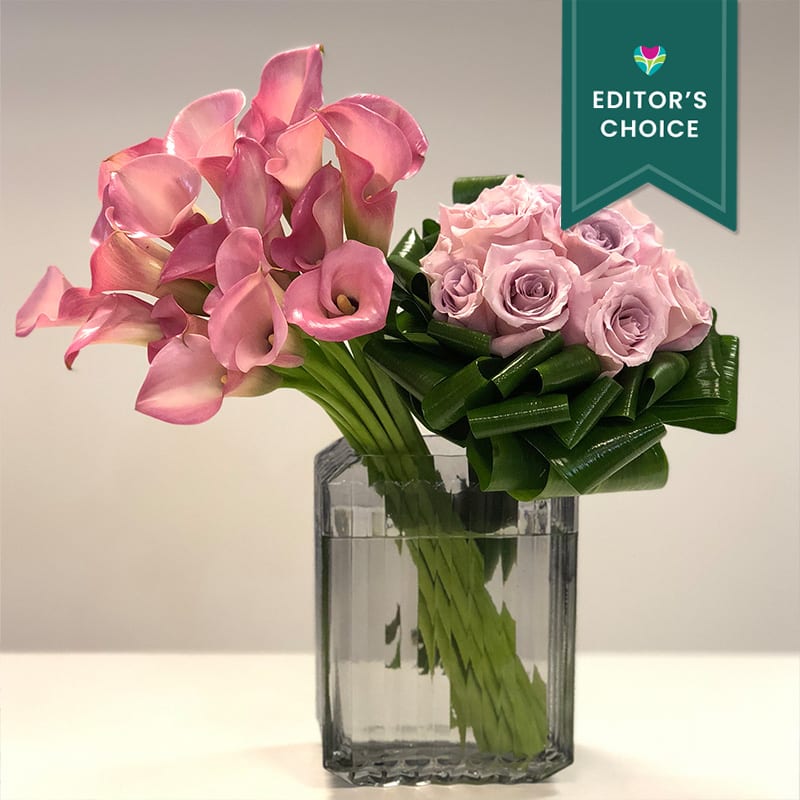 Pink calla lilies and blush roses accented with folded aspidistra leaves in