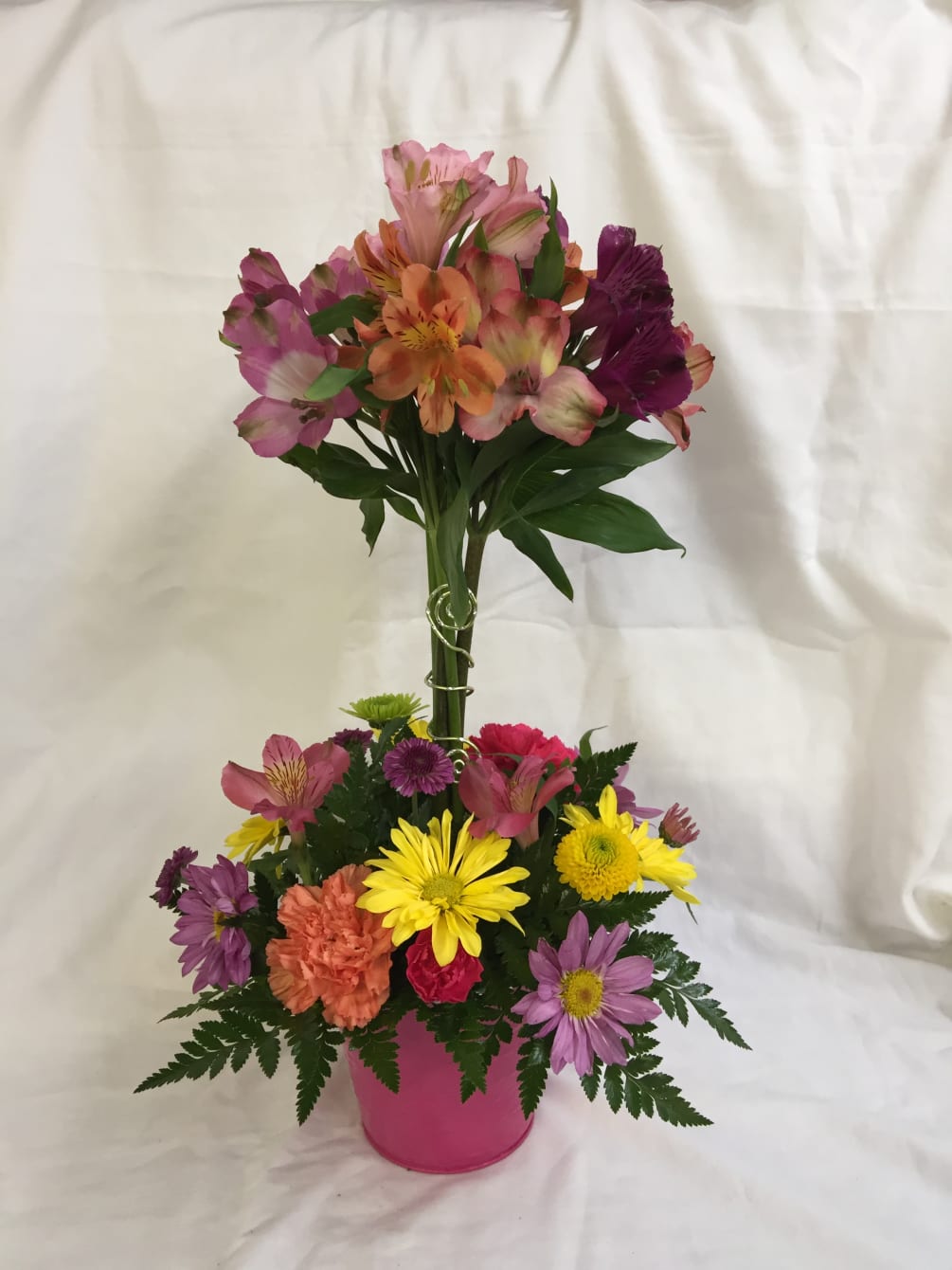 Topiary of alstroemeria blooms with assortment of fresh flowers below. Container color