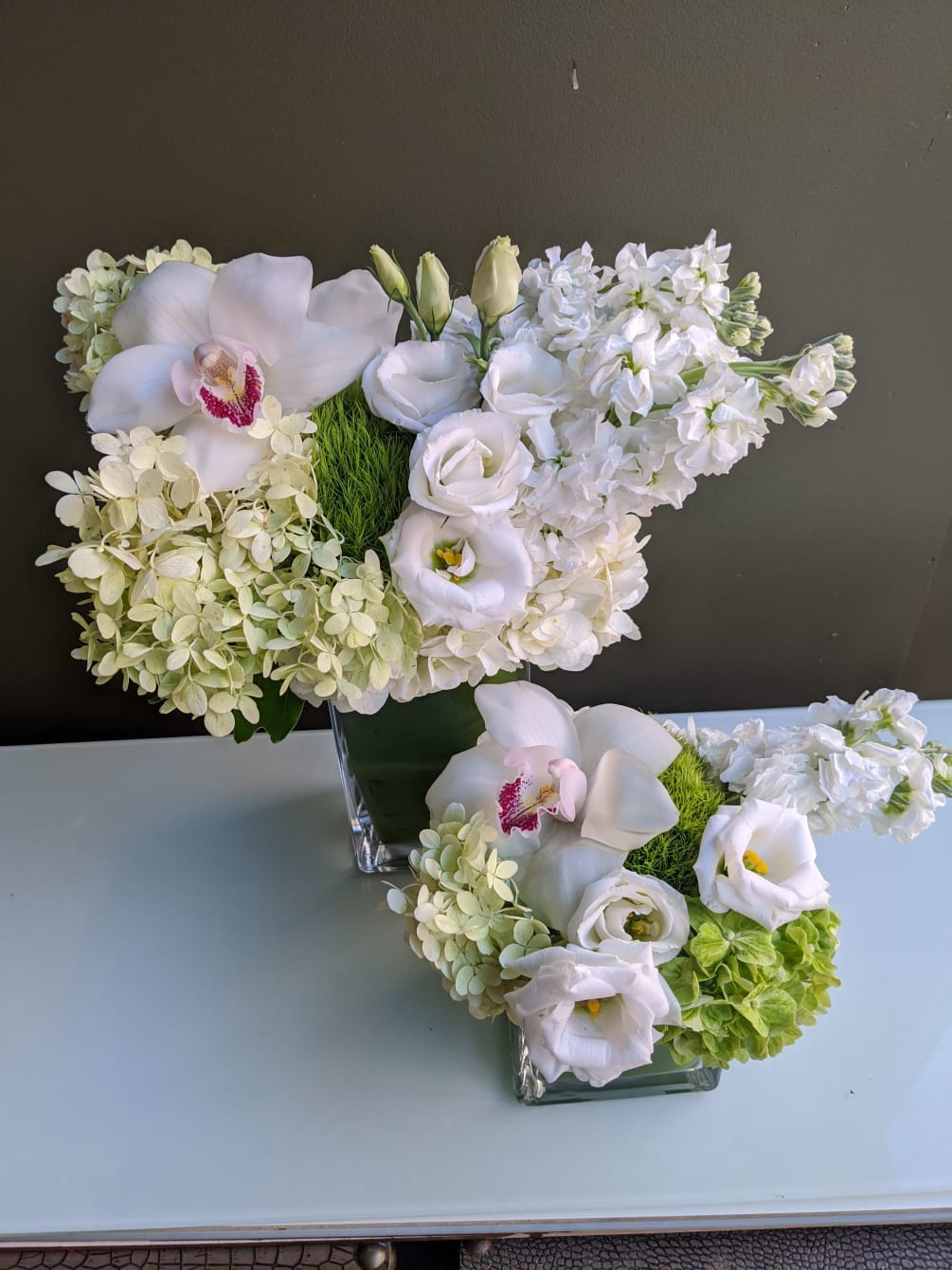 this design features 2 arrangements with white and green hydrangea, dianthus, orchids