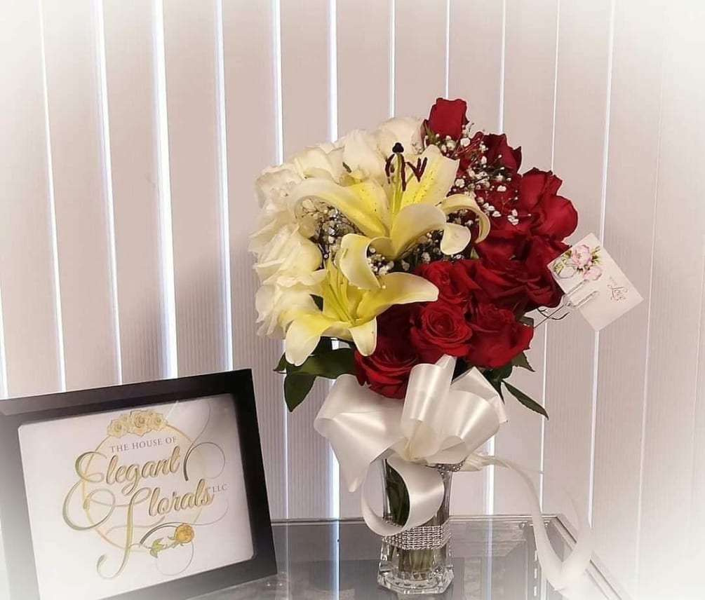 This is a unique vase arrangement filled with roses and yellow lilies.