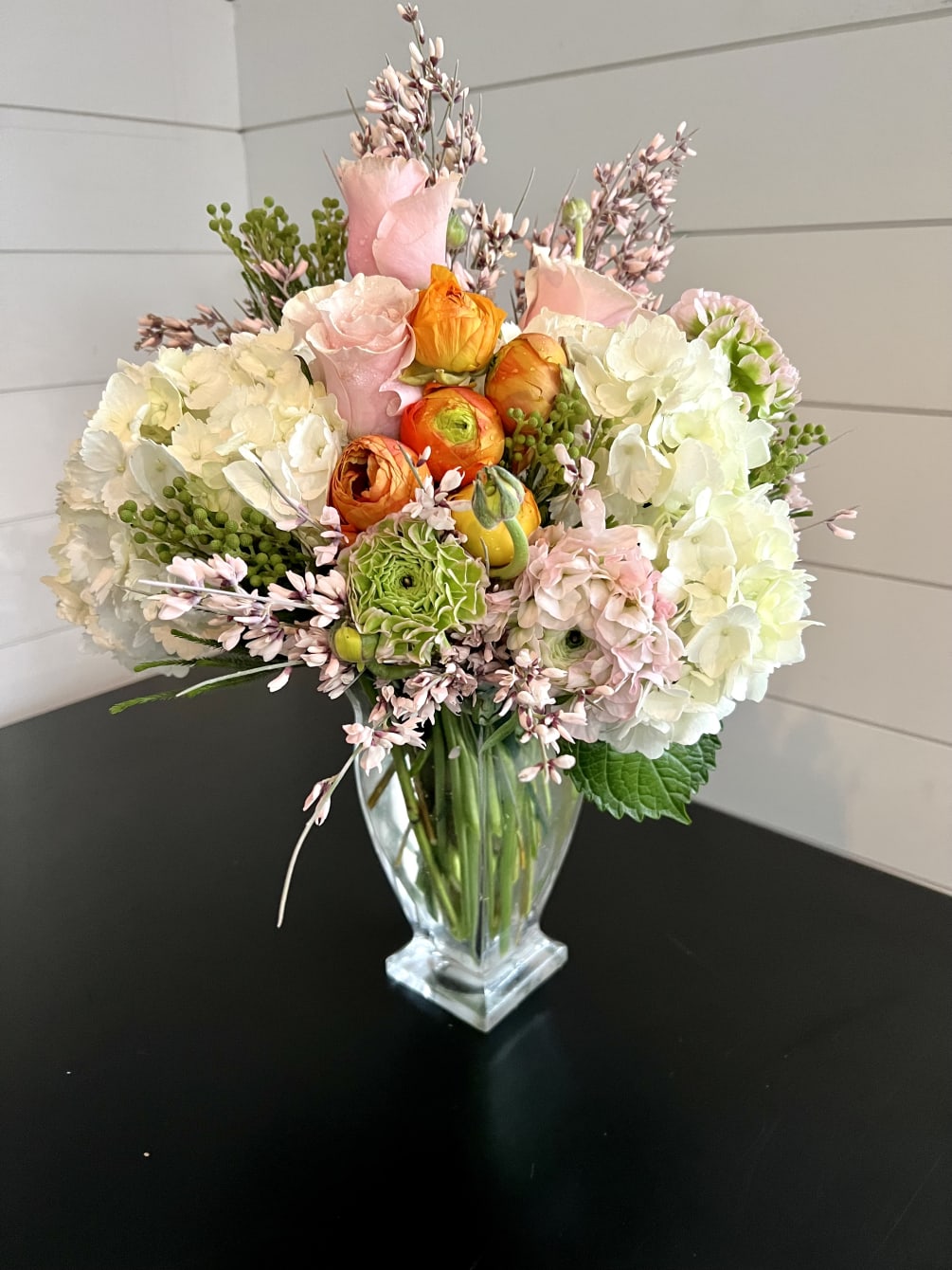 A lush collection of garden florals artfully arranged in an attractive clear