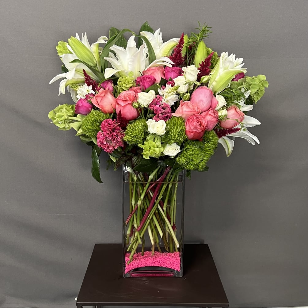 This floral arrangement is designed with white oriental lilies, imported roses, and
