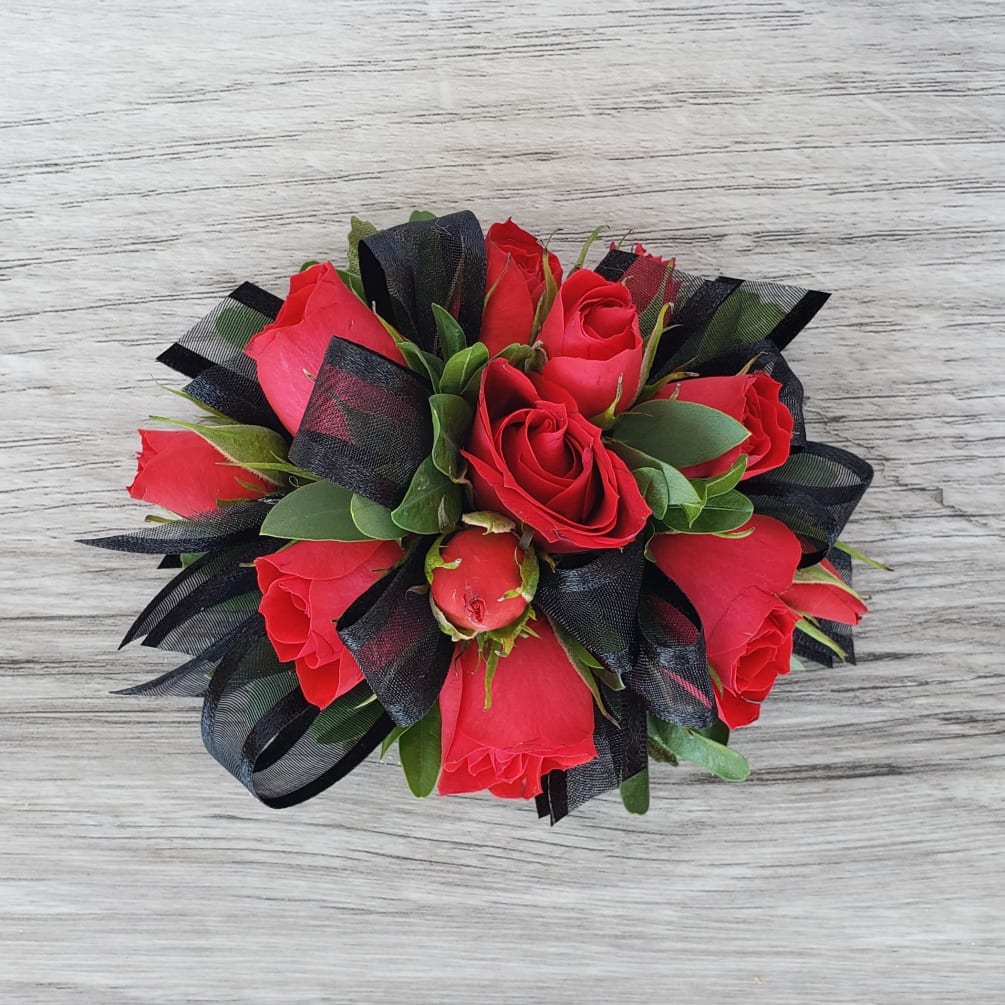 This corsage features red spray roses, accent greenery and black ribbon. If