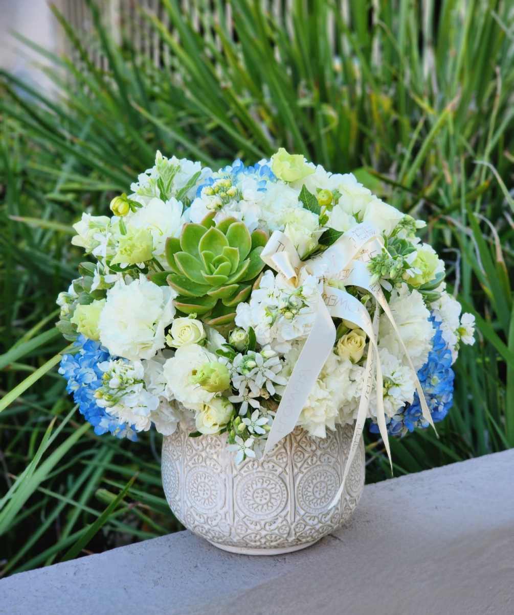 A succulents, blue hydrangeas, and white flowers floral arrangement in a vase