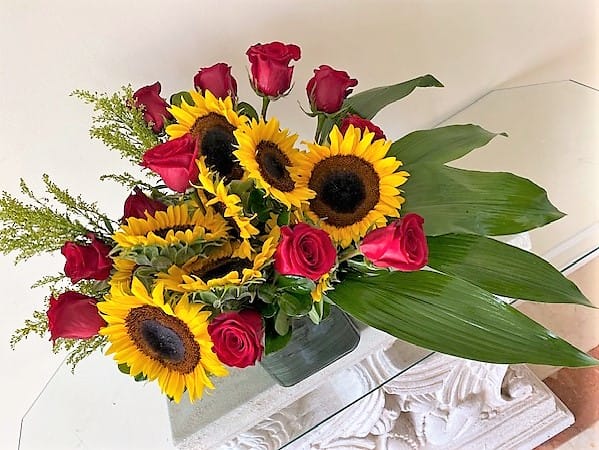 10 Sunflowers with 12 Red Roses arranged in a glass vase