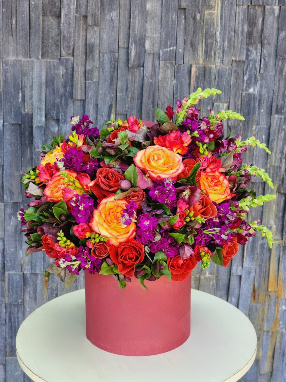 A floral mix featuring orange and red roses, along with other fall-style