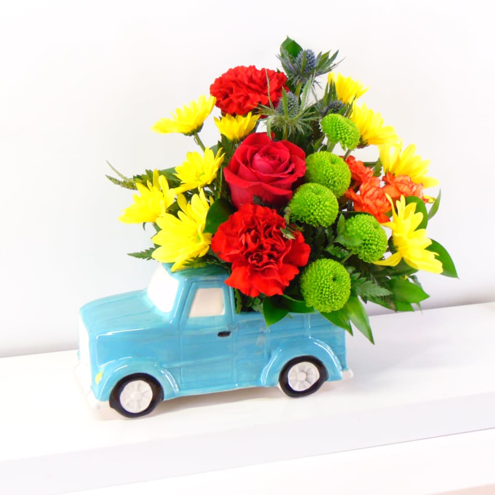 A timeless fresh arrangement with red carnations, yellow daisies and green button