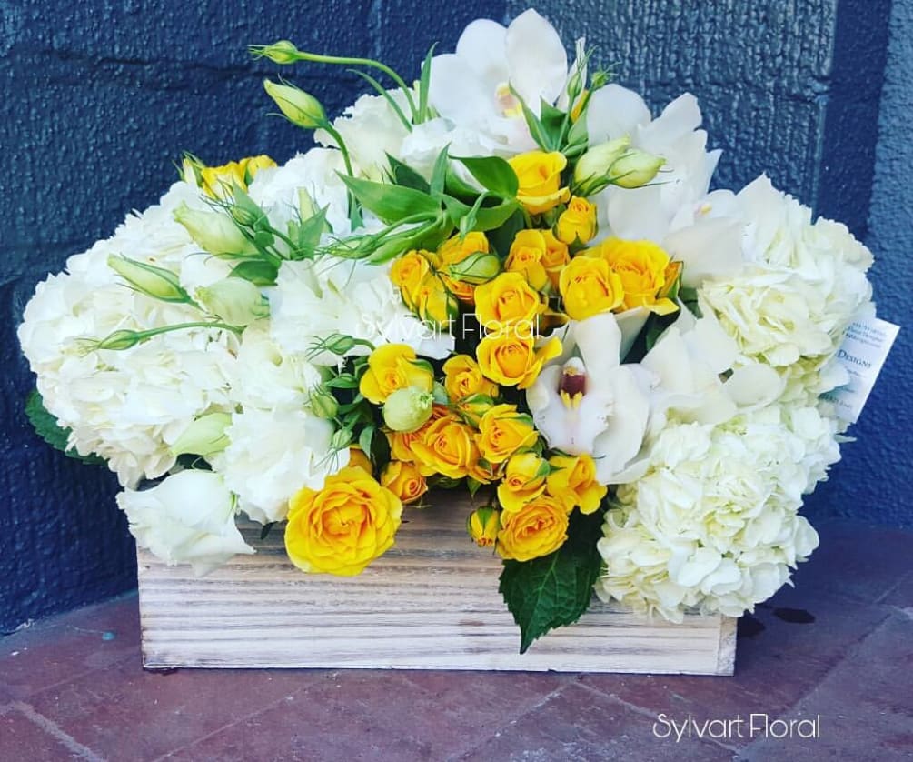 This lovely piece includes white Hydrangeas, Yellow Spray Roses, with Cymbidium Orchids