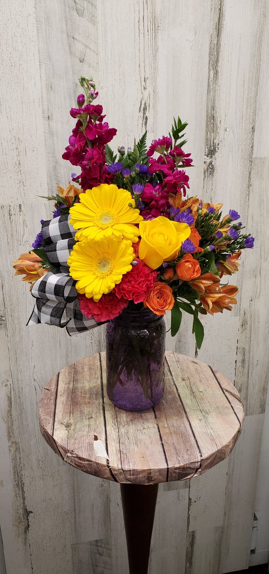 A colorful large mason jar filled with bright fresh flowers for the