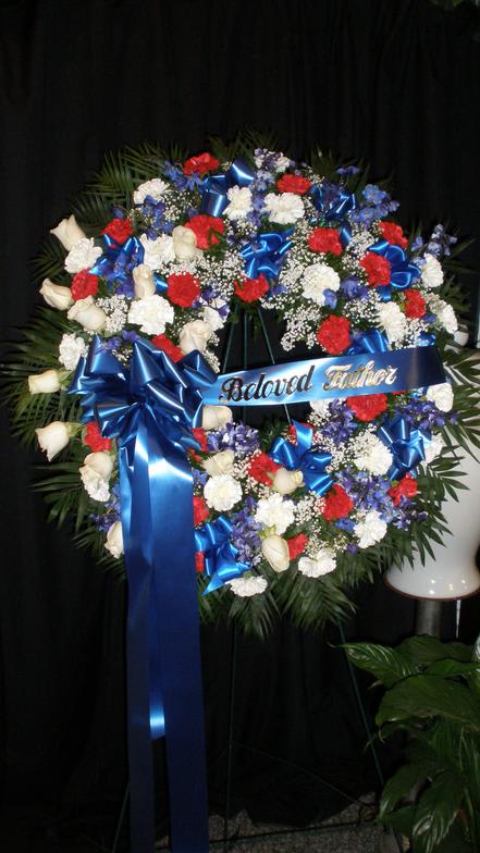 Patriotic remembrance piece with red, white, and blue flowers surrounded by tropical