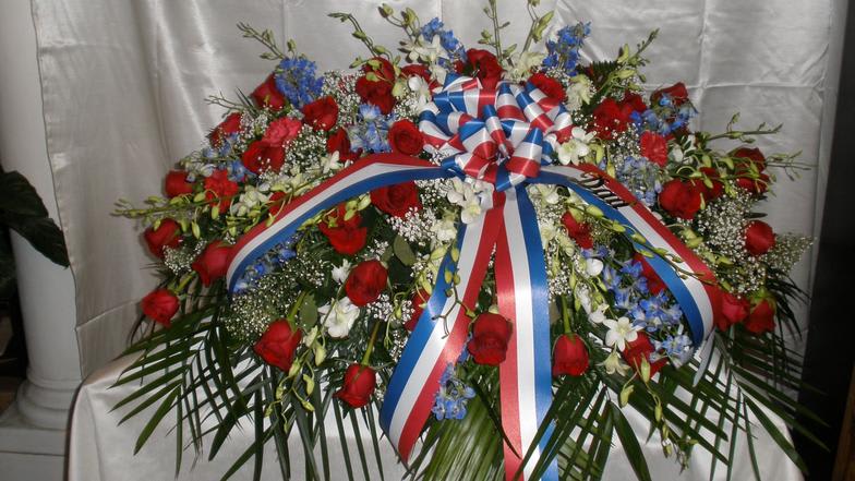 Large patriotic casket spray with red roses.