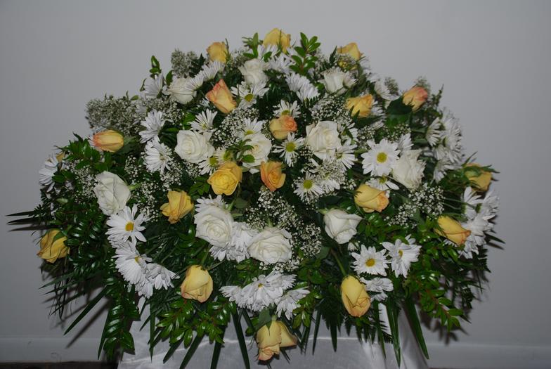 Beautiful spray with white and yellow roses, white daisies, and green plants.