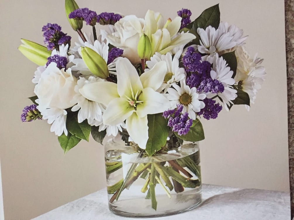 White lilies, roses and white daisy mums with purple status and greens