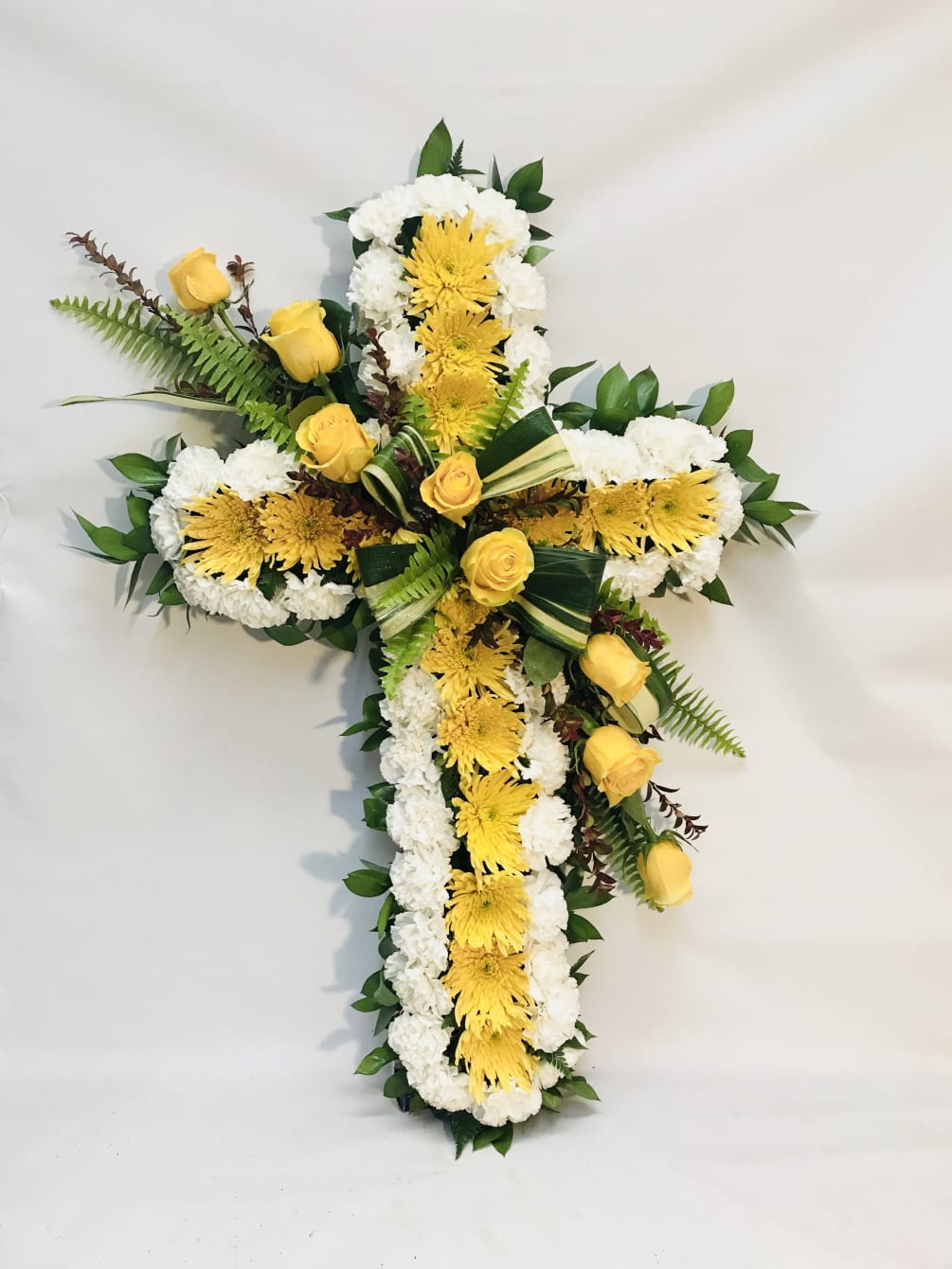 This sympathy cross is designed with yellow spider mums, surrounded by white
