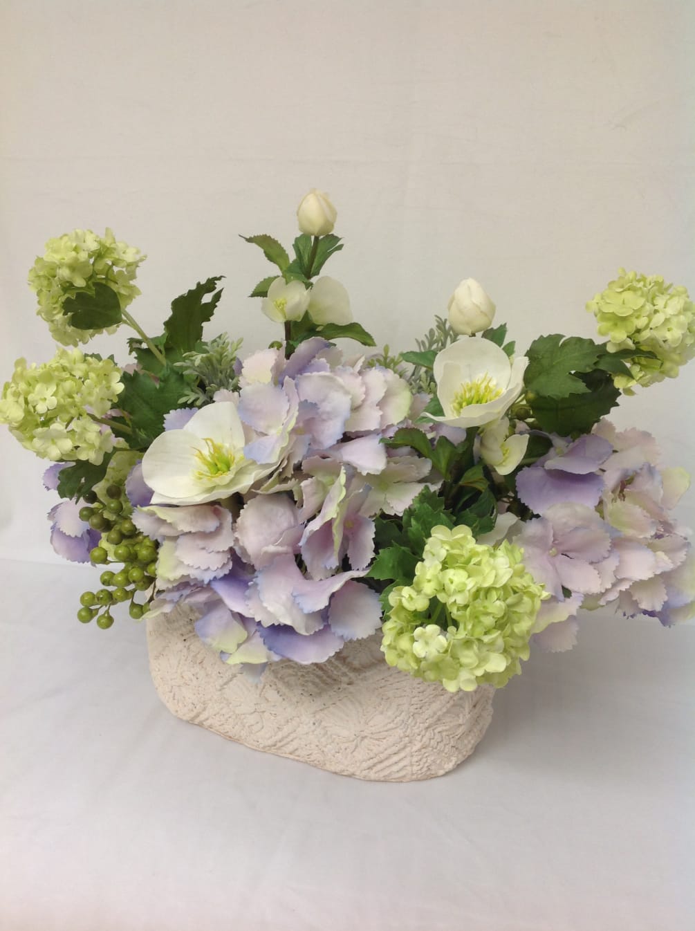 Casual curated assortment of faux hydrangeas, viburnum and hellebores 