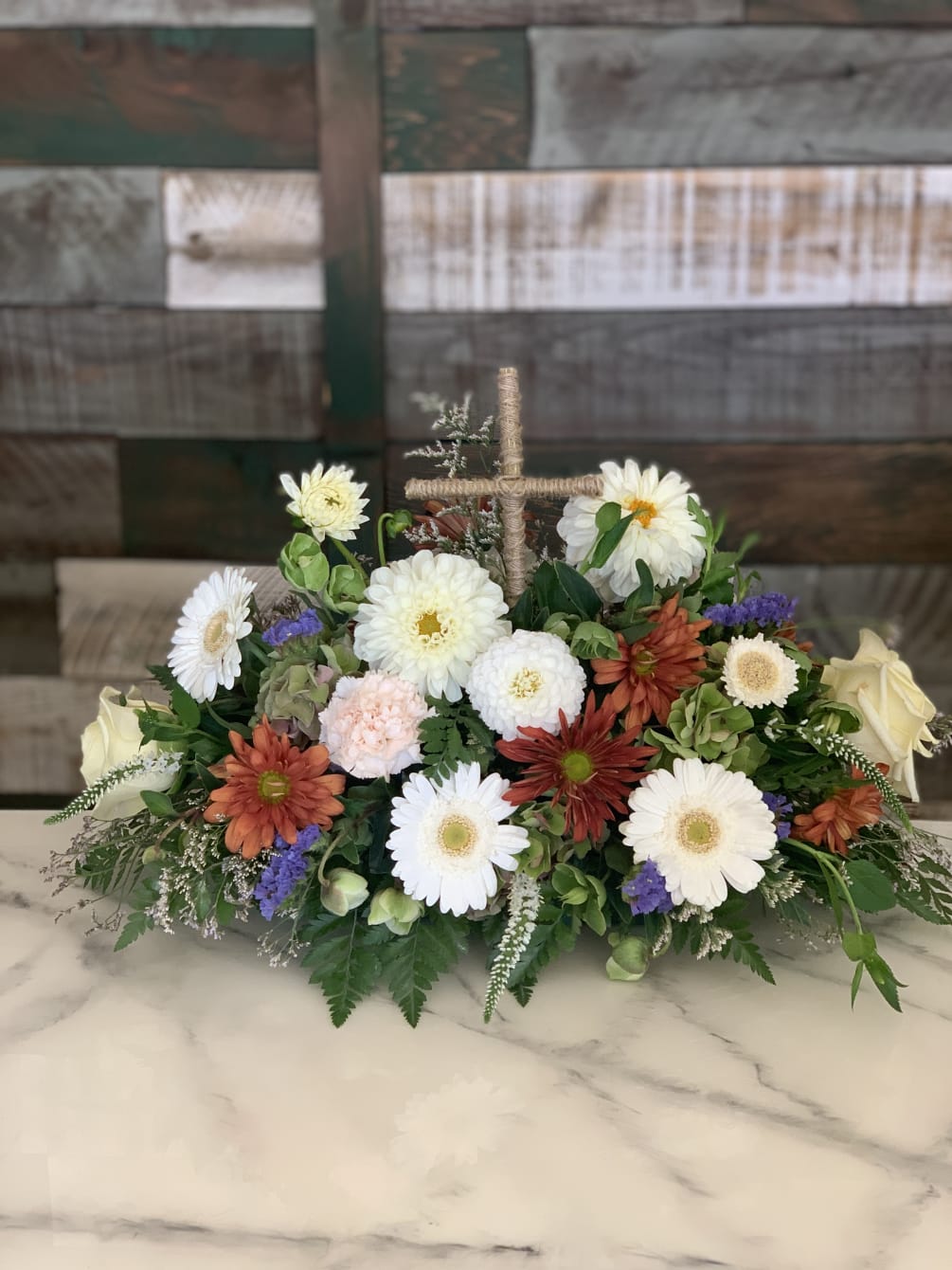 Cross with surrounding seasonal florals for sympathy and condolence.