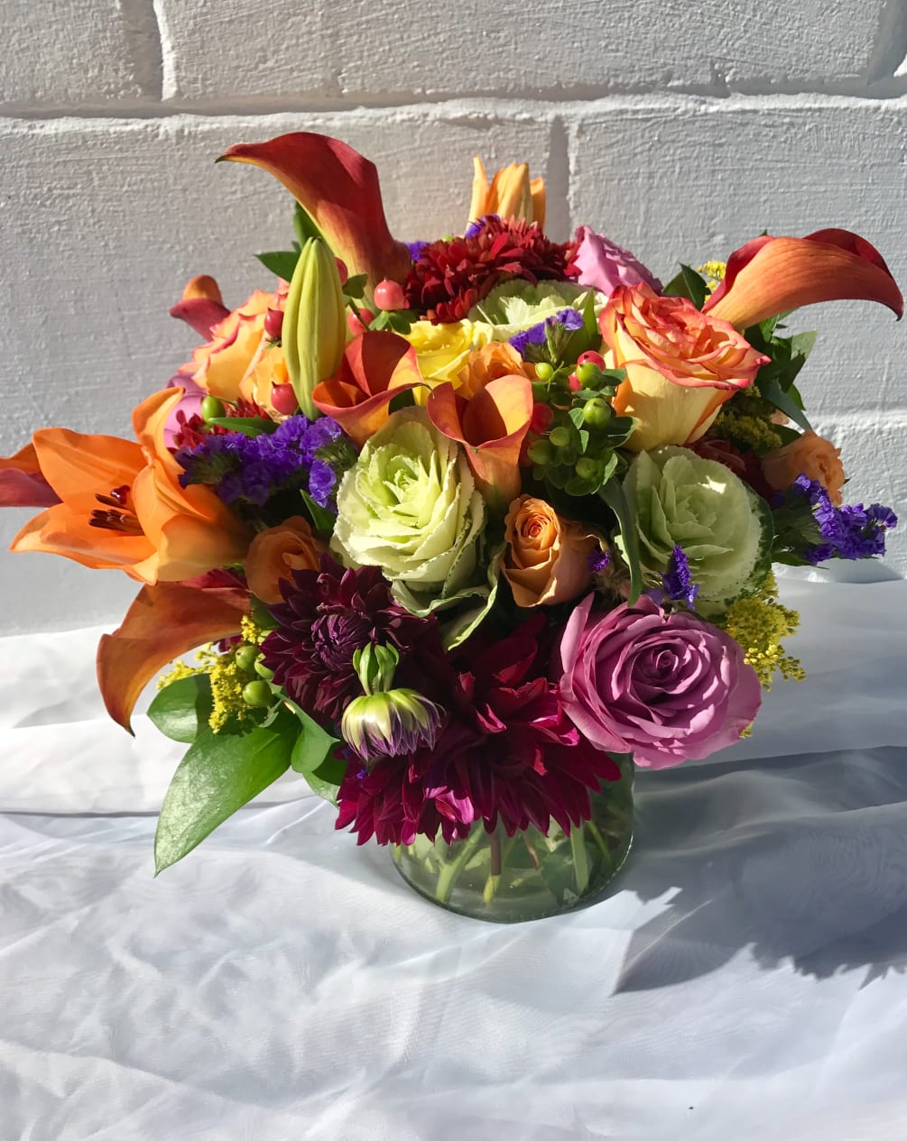 Bright fall flowers designed in cylinder vase