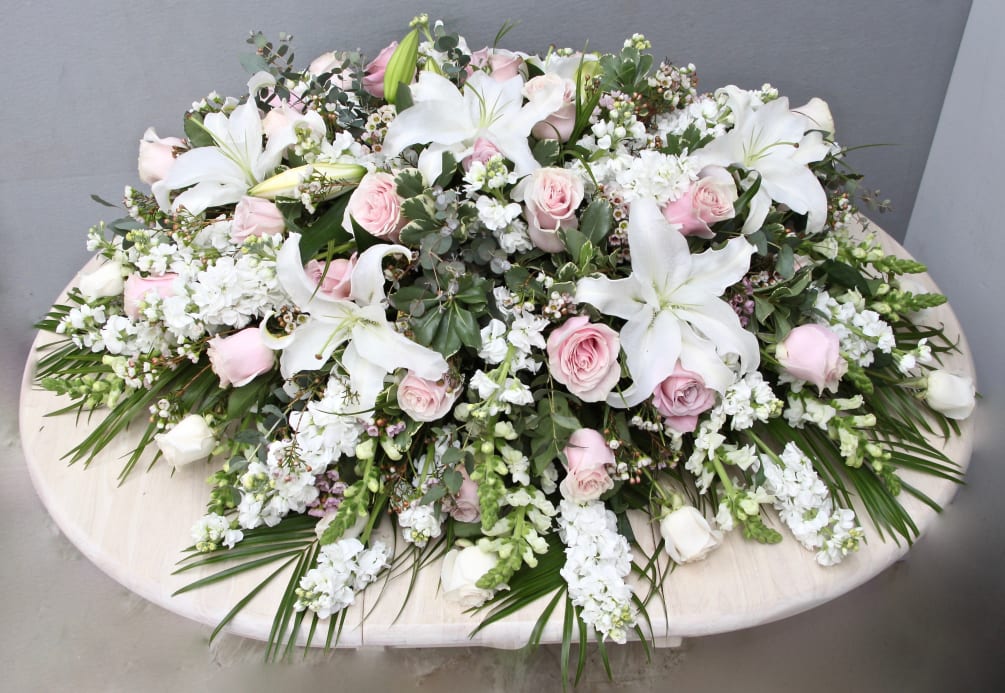 This casket arrangement is made with pink and white roses, stargazer lilies