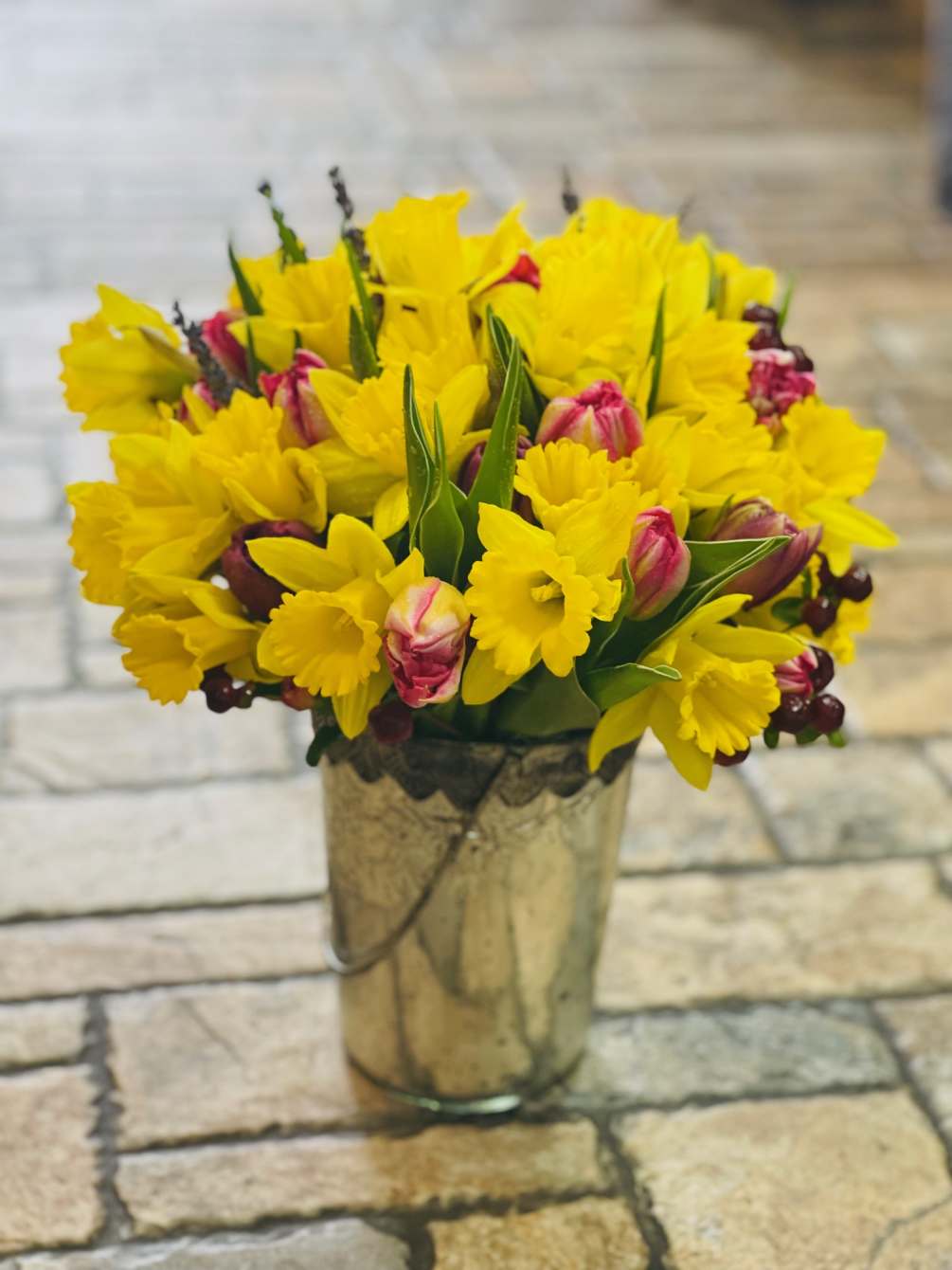 BEAUTIFUL BRIGHT YELLOW DAFFODILS EMPHASIZED WITH CONTRASTING TULIPS AND BRIGHT, ROUND BERRIES.
