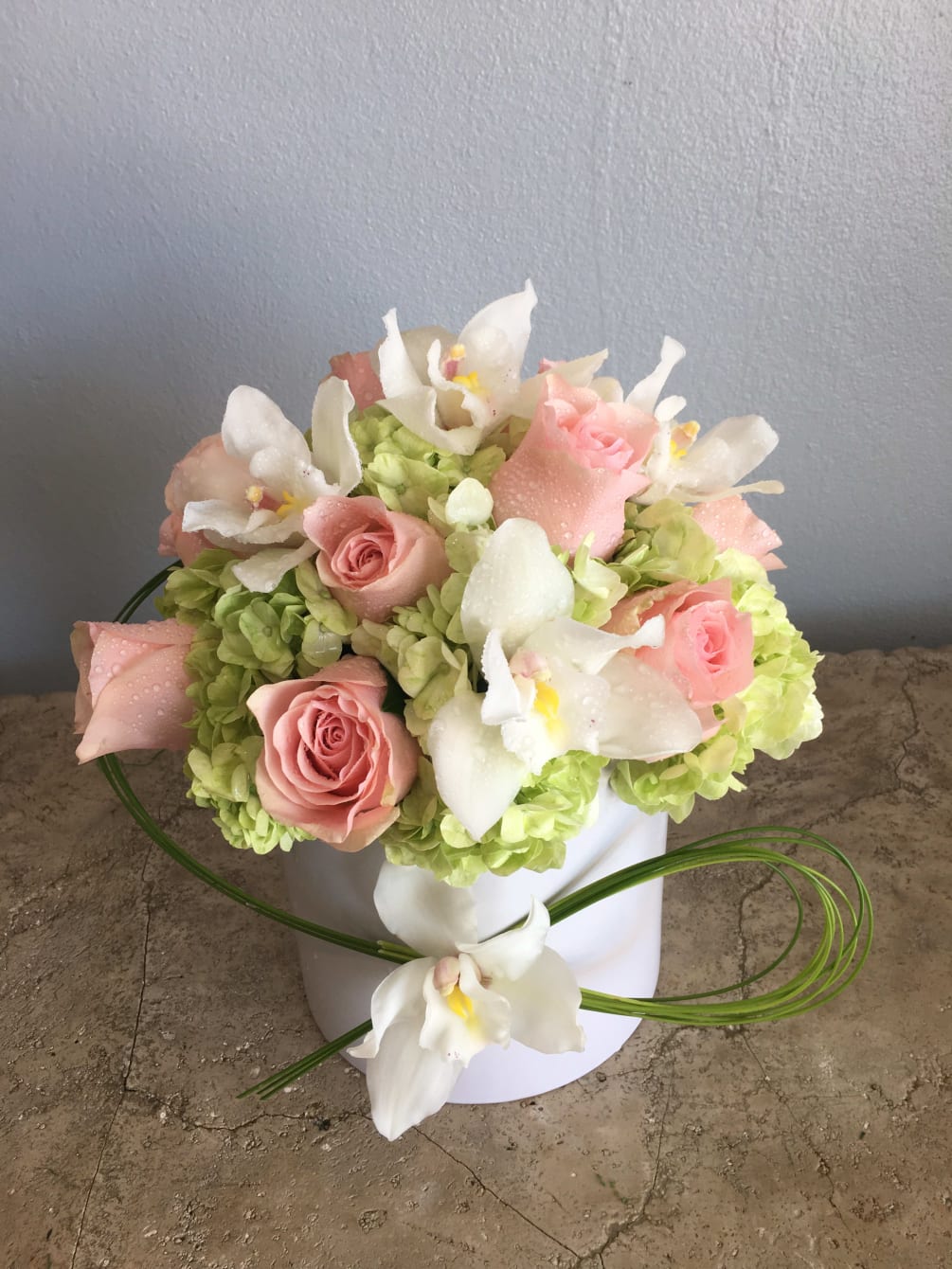 High style design with whites, greens, peach featuring cymbidium, hydrangea and roses.