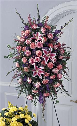 A lavish standing spray in pink and lavender tones. Pink roses, Stargazer