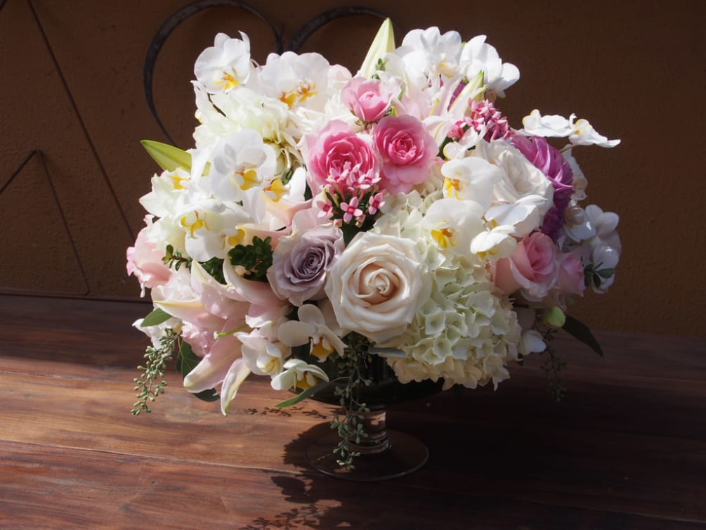 Clear vase with white, and pastel pinks flowers like 
roses, spray rose