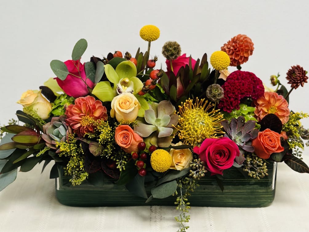 Low centerpiece, in autumn hues and other vibrant colors. Flowers are hand