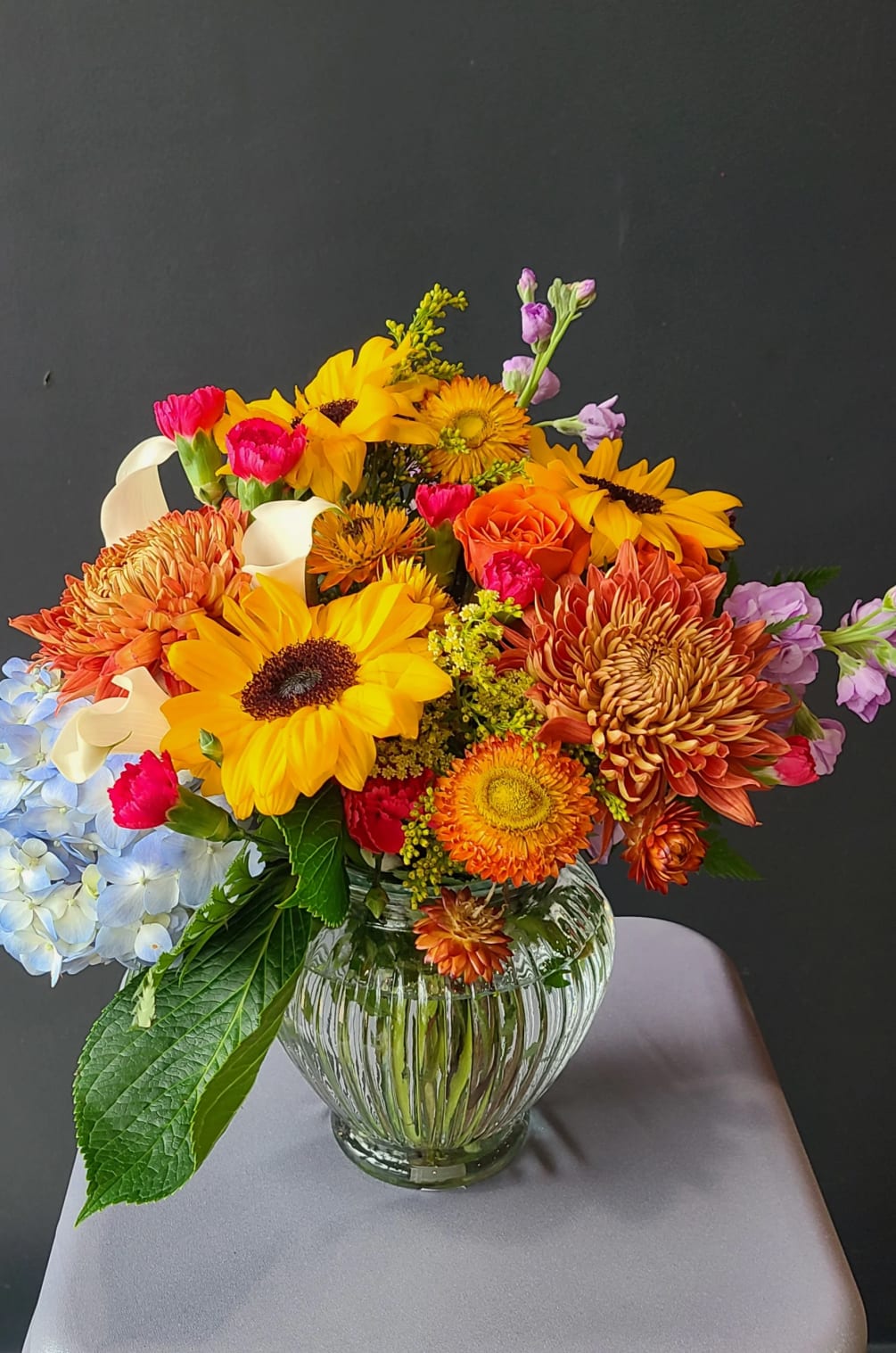 Like a crisp fall day, this arrangements of mums, sunflowers, calla lilies