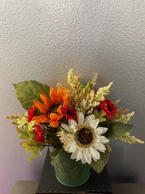 bouquet of artificial flowers arranged in a seasonal tin vase.