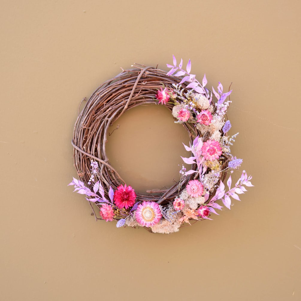 The Lover wreath is a grapevine wreath bursting with preserved colorful flowers.