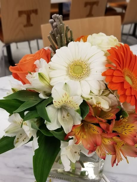 nice little mix of orange and white fresh flowers in a glass