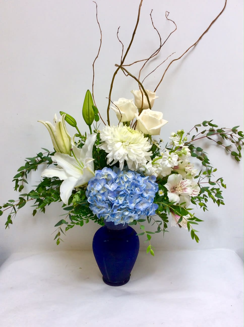This serene design features a blue vase with white and blue blooms