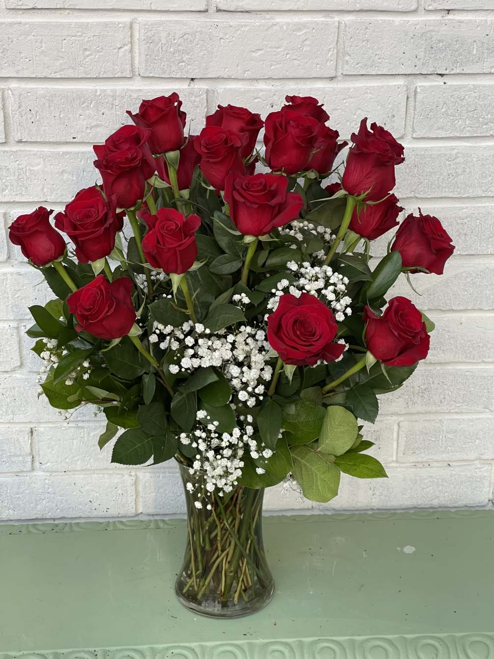 24 Long stem red roses in a clear vase with baby breath