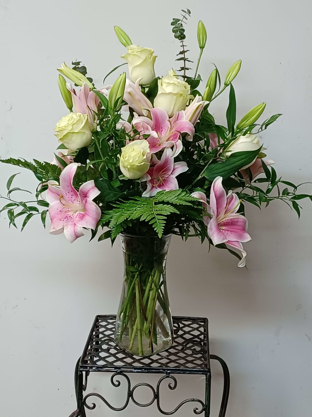Request  roses, lilies Colors arranged in a vase with greens