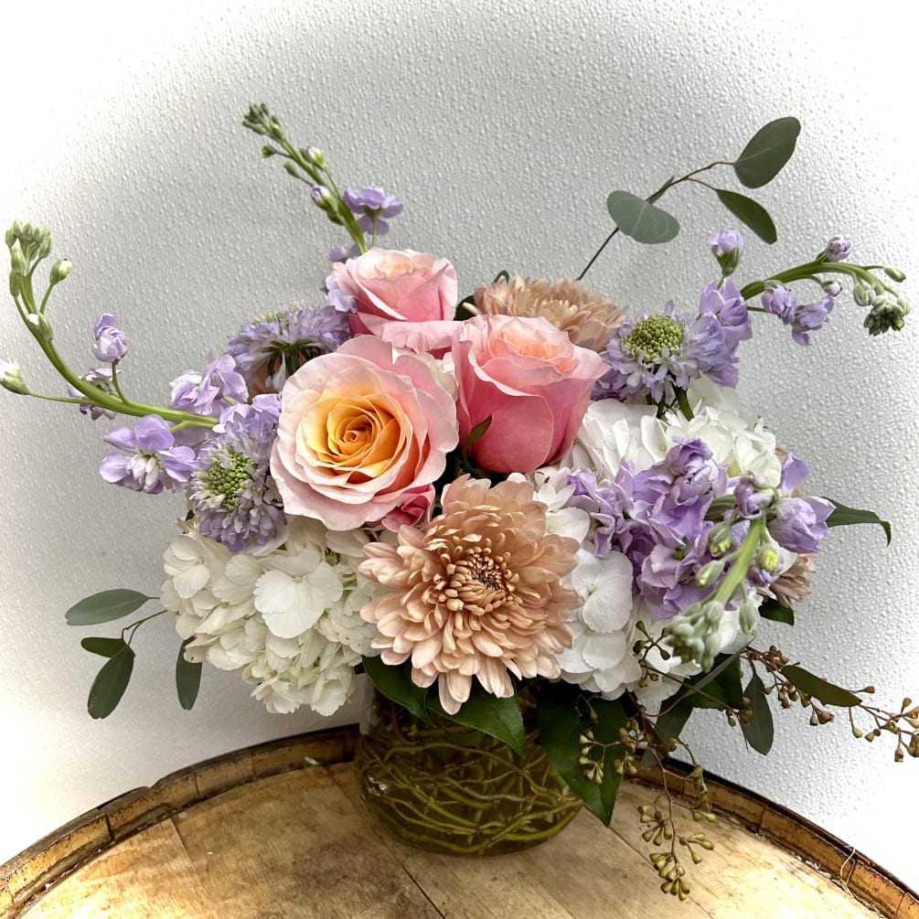 Soft palette of florals in curly willow filled glass vase and eucalyptus