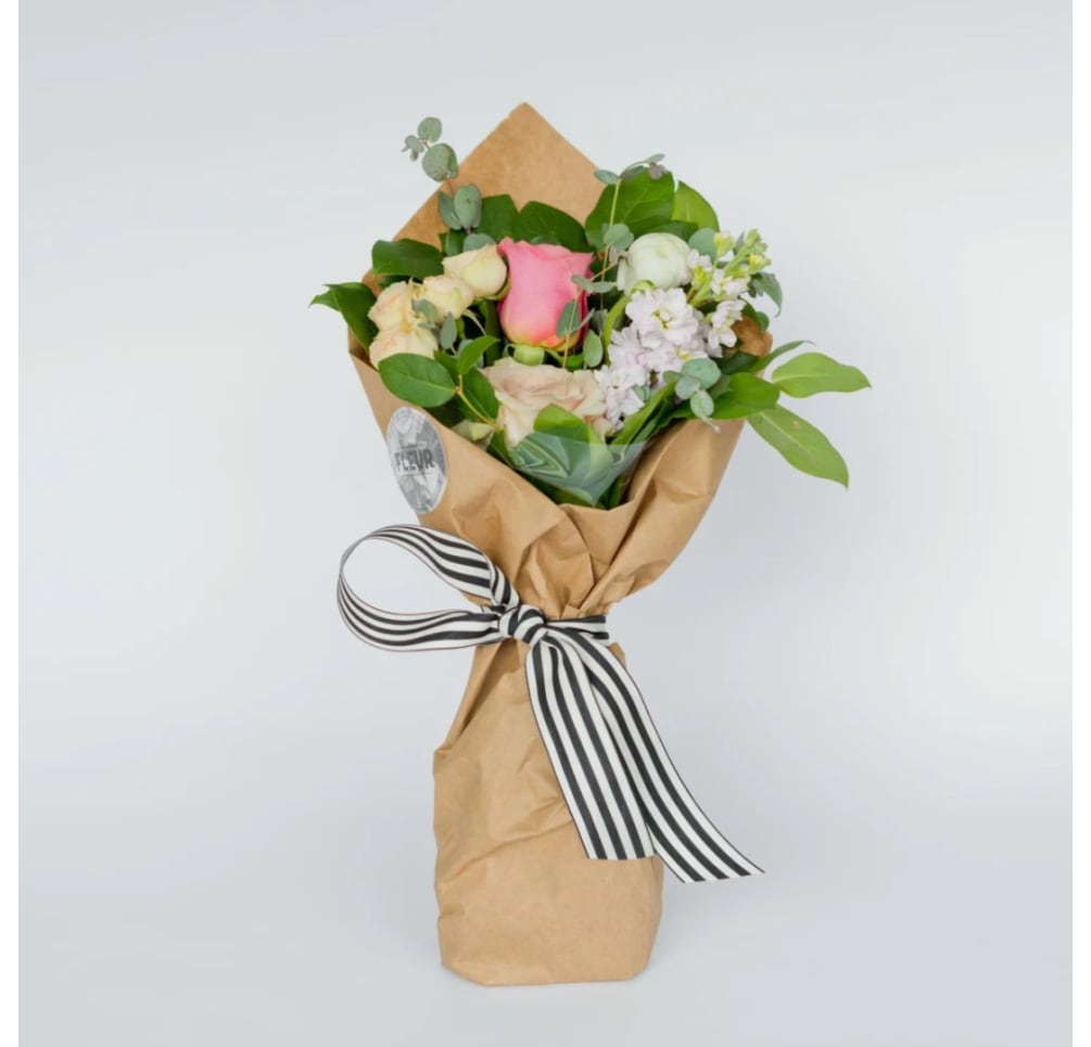 Seasonal blooms and foliage packaged in a classic brown market paper. Includes