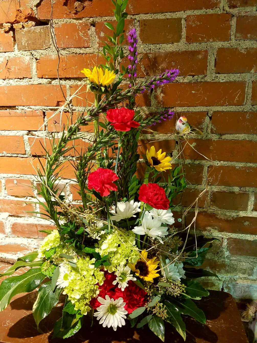 This bouquet includes hydrangeas, sunflowers, carnations, daisies, with liatris manipulated to give