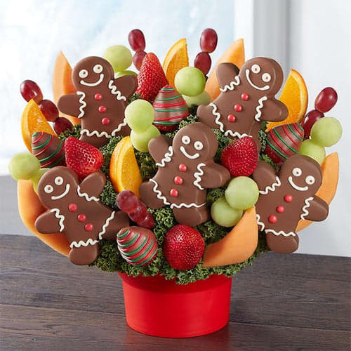Fruit arrangement of gingerbread man-shaped pineapple slices dipped in chocolate, and decorated