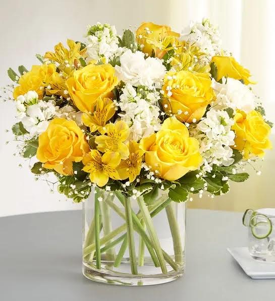 Round arrangement with yellow roses and yellow alstroemeria; white carnations and, accented
